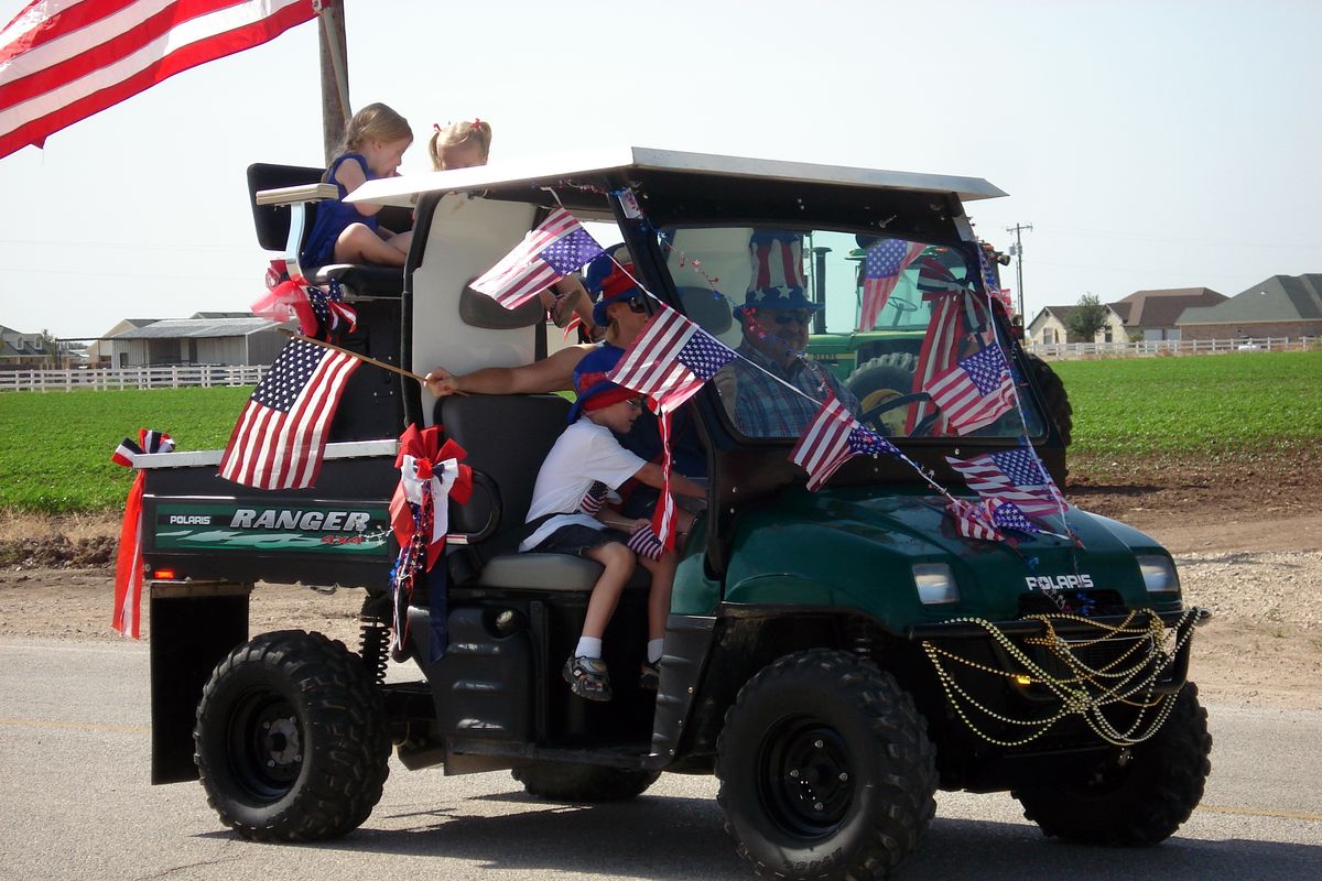 Golf cart covered in flags with kids aboard