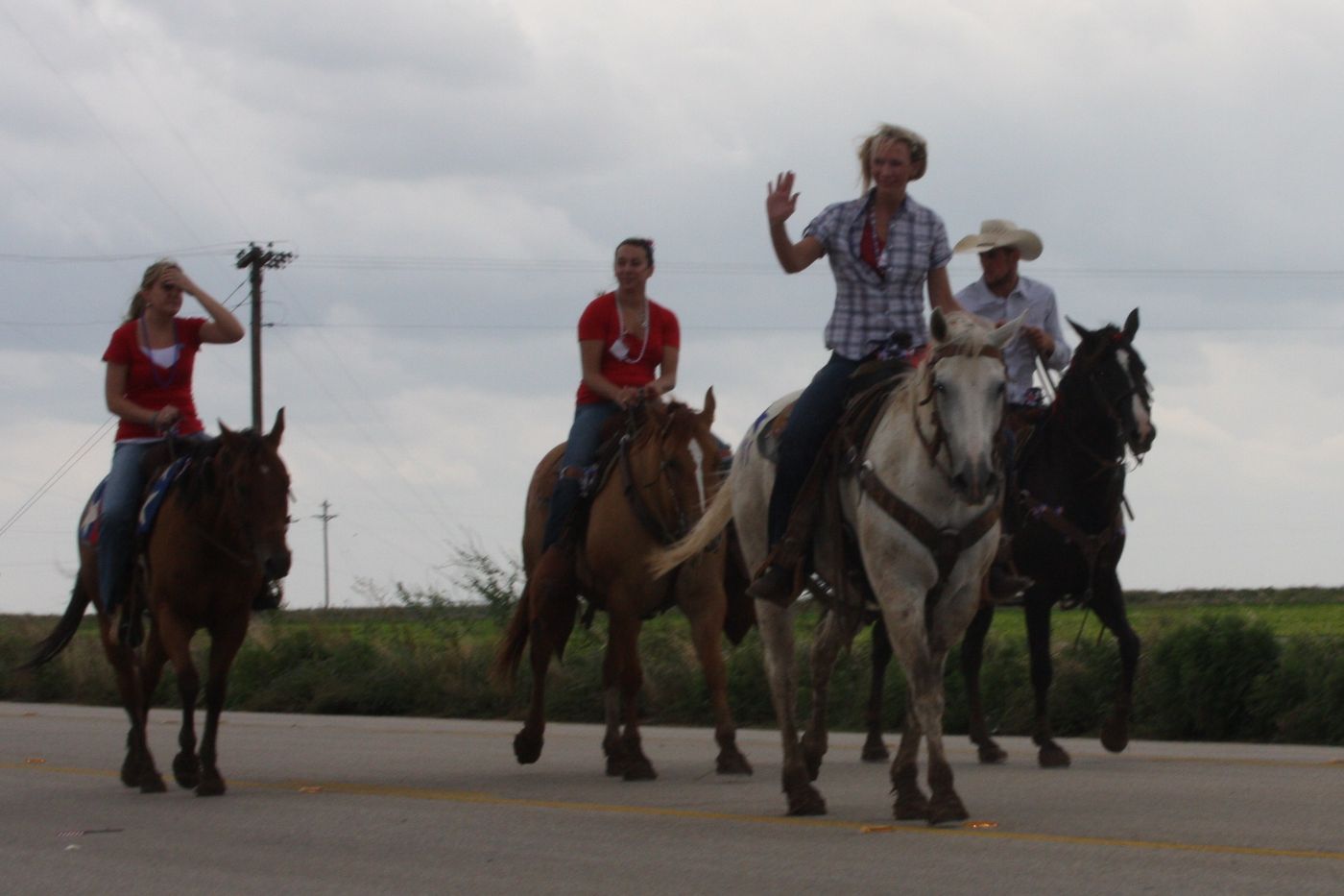 Riders on horseback waving to the crowd
