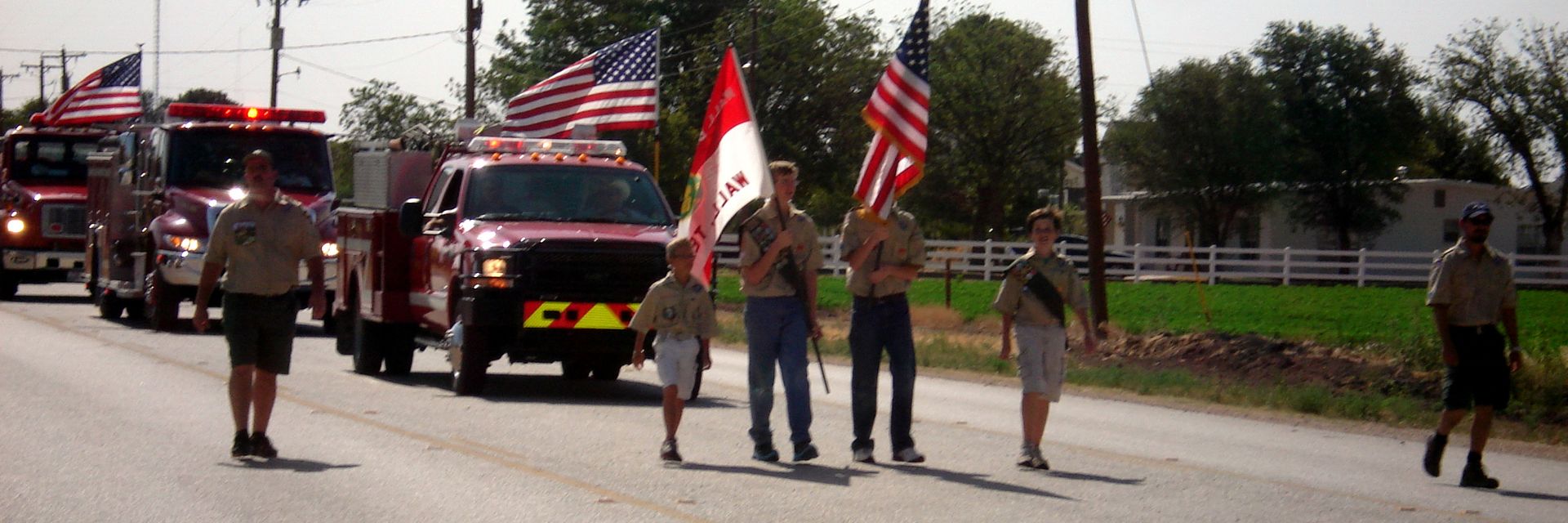 Flag bearers leading a line of fire trucks down the parade route
