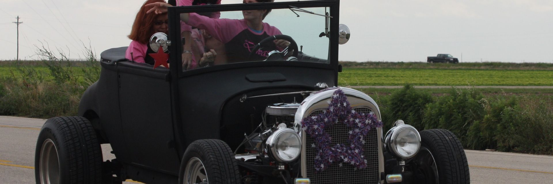 Hot rod carrying kids waving flags