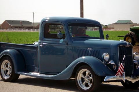 Vintage blue Ford pickup with flags