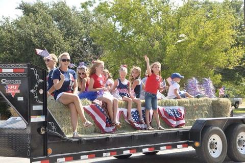 Hay trailer float packed with waving kids