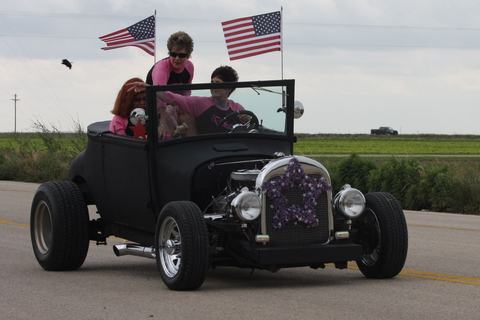 Black hot rod carrying kids with flags